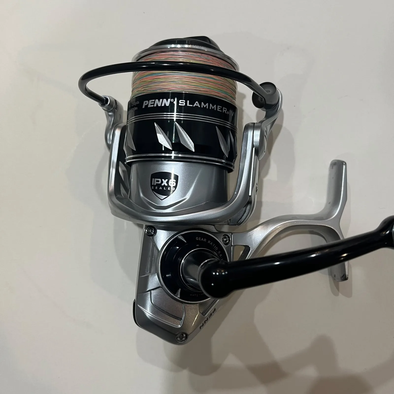 Used Penn Slammer IV DX 5500 spinning reel from the front, spooled with multicolour braid