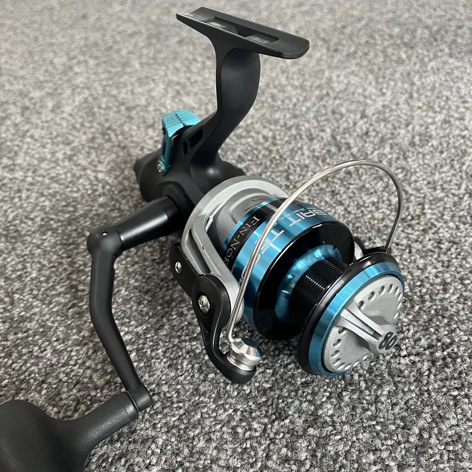 Used Fin-Nor Bait Teaser BT80 spinning reel, black and teal, three-quarter view